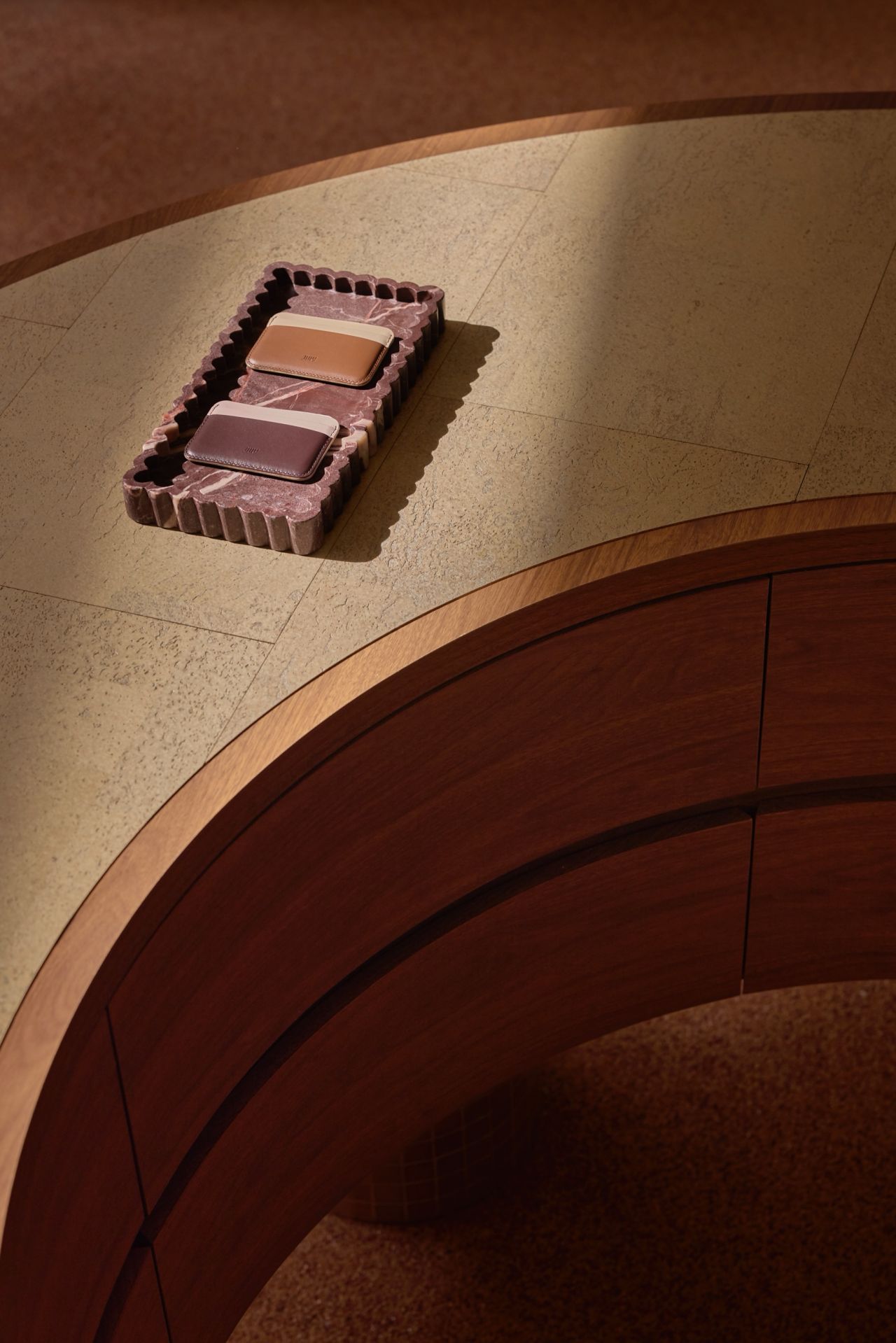 Curved timber counter with stone top and leather goods display