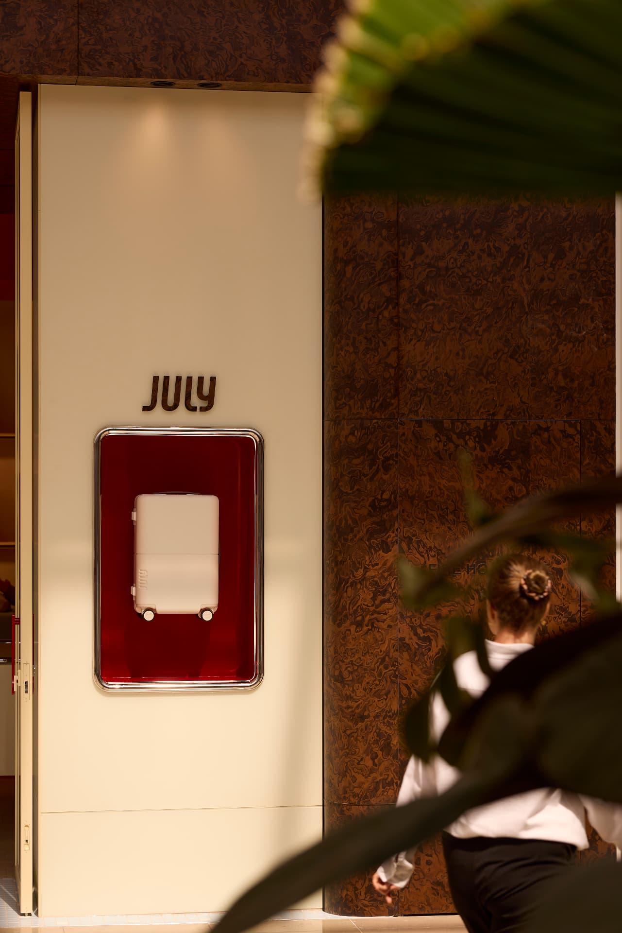 July signage on cream joinery with red lacquer display vitrine and burl veneer wall