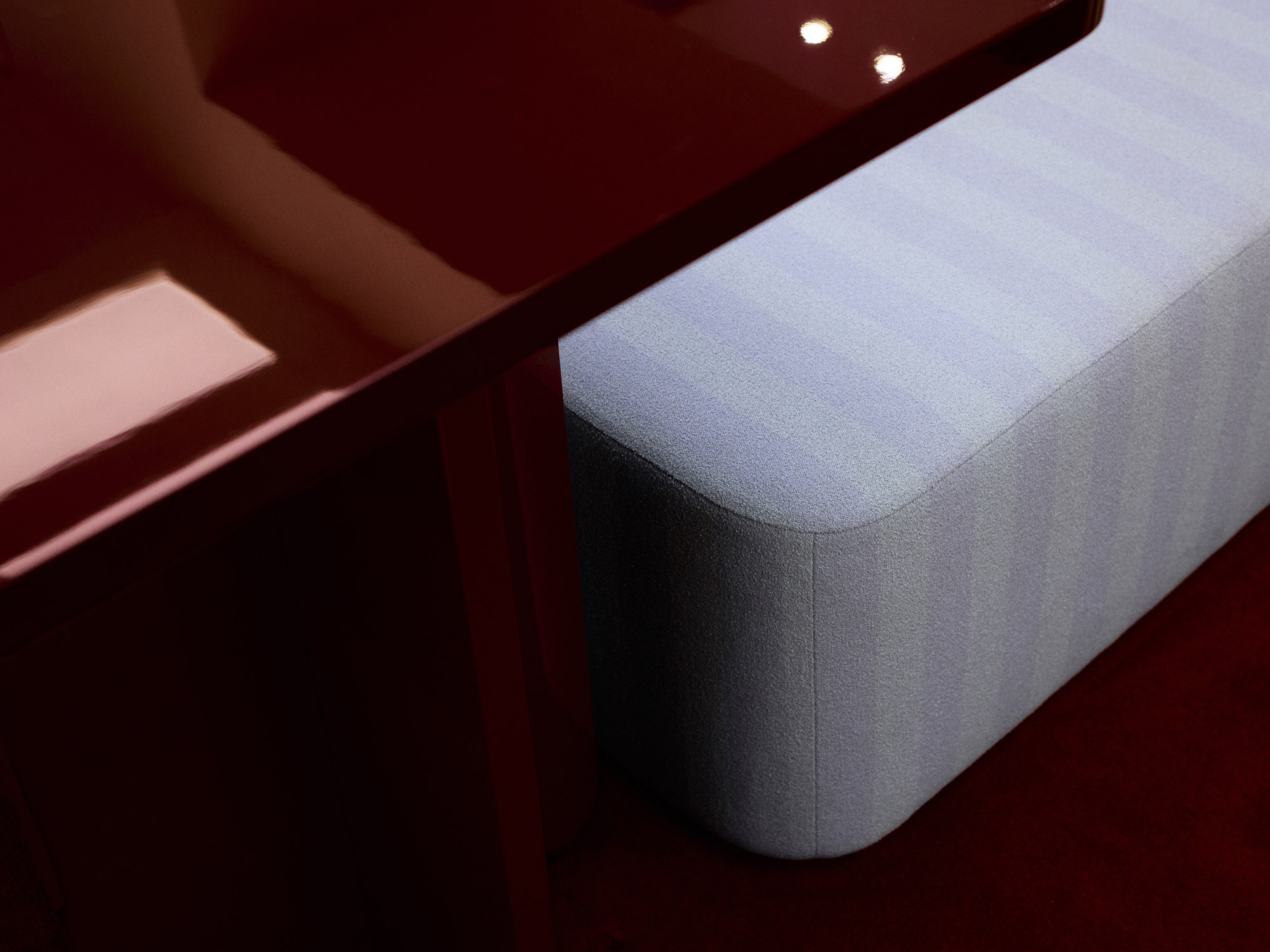Detail of oxblood lacquer table edge and upholstered bench seat