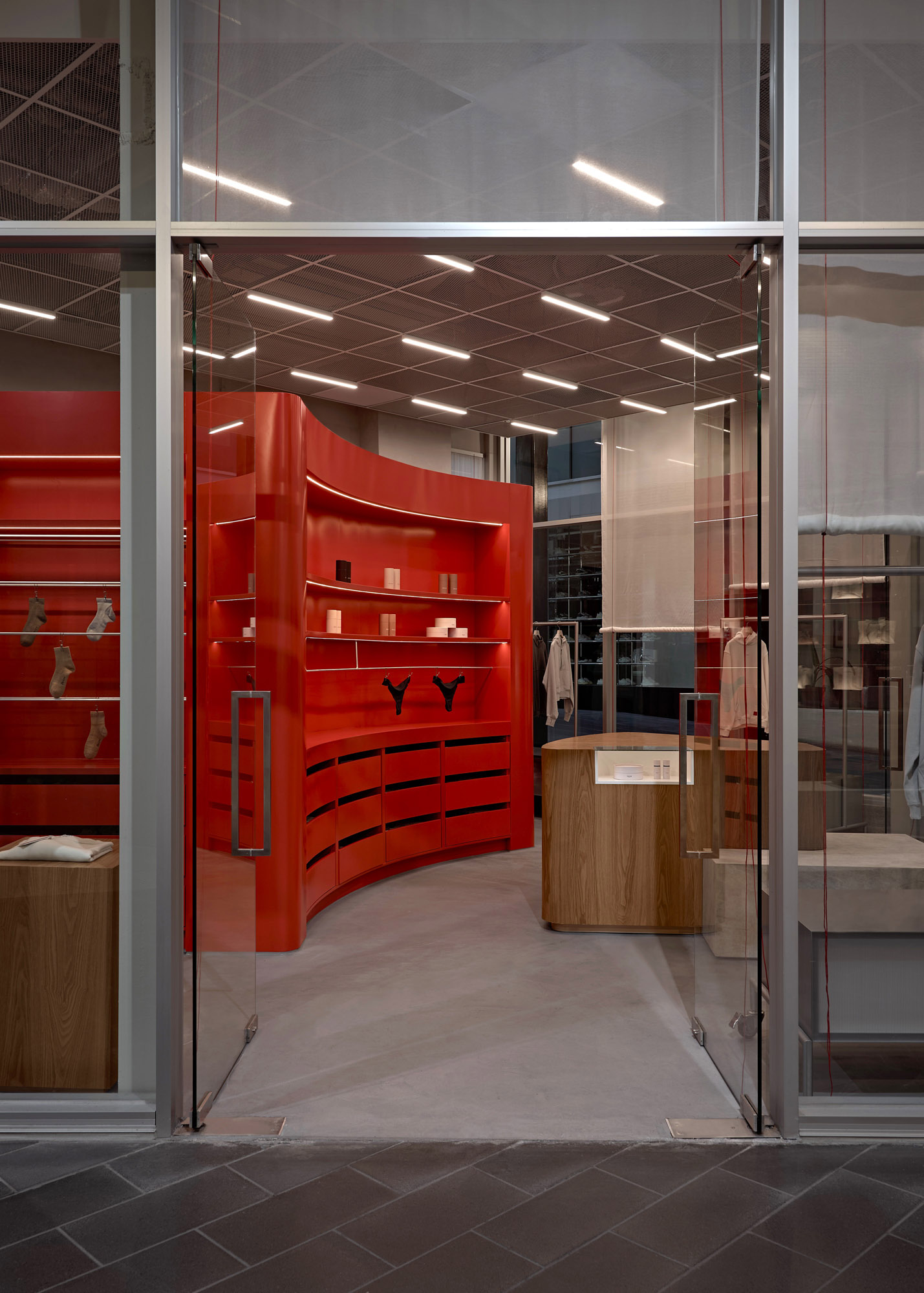 Curved high-gloss red lacquer wall with backlit shelving and oak cash wrap