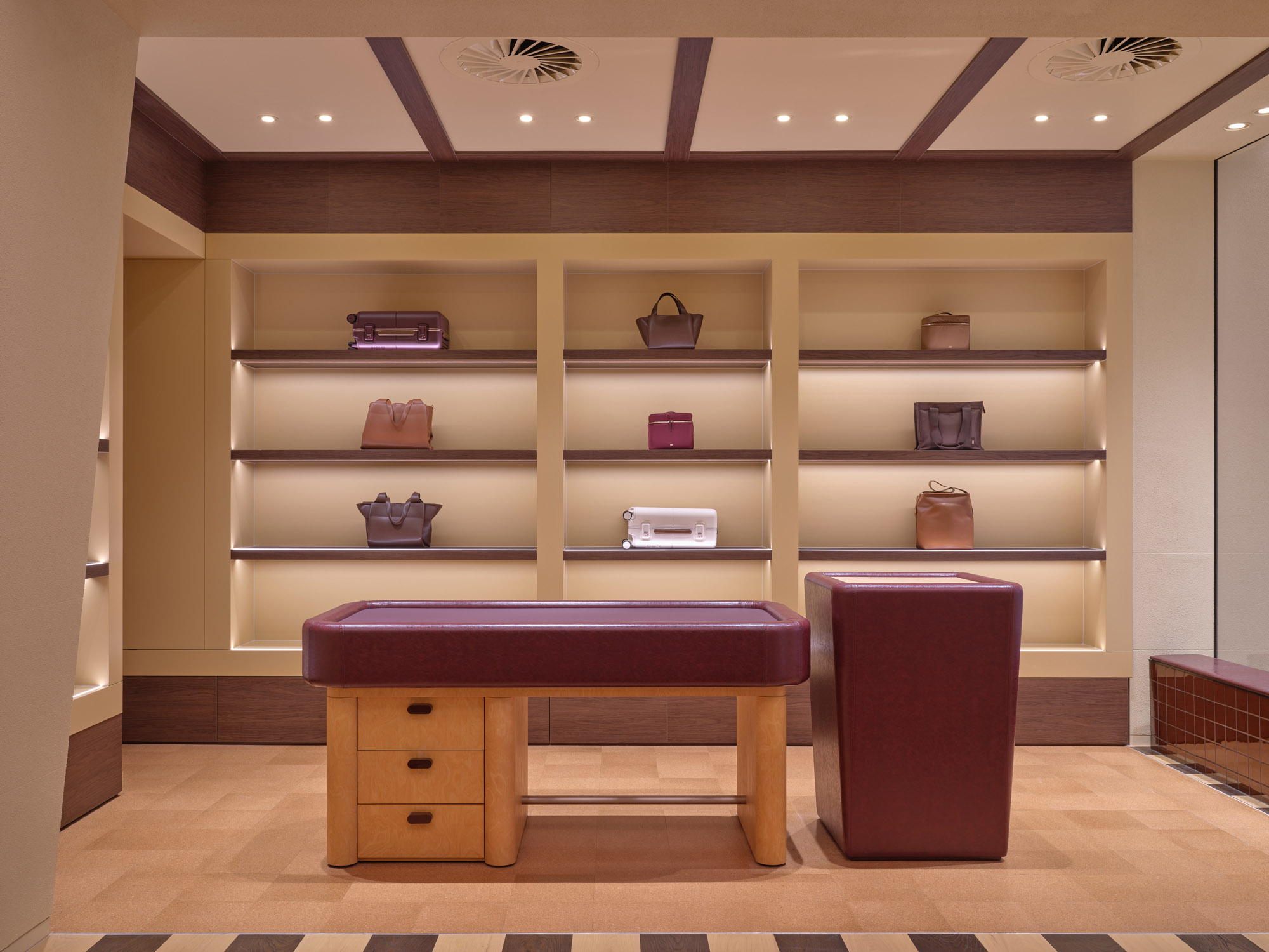 Backlit shelving bays with walnut reveals and burl timber display table